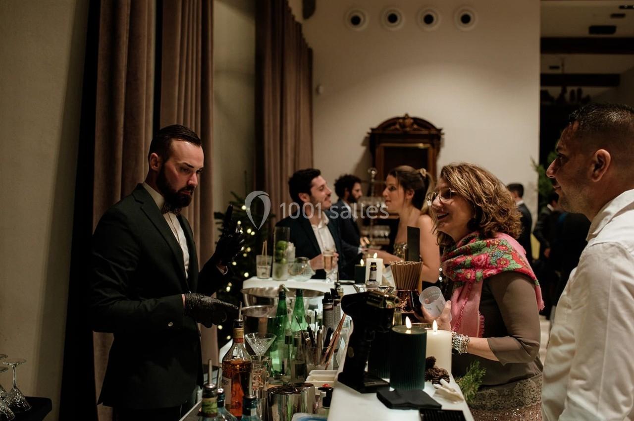 Un barman sert des boissons à des invités lors d'un événement dans un cadre élégant et chaleureux.