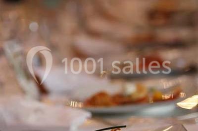 Façade d'un bâtiment éclairé en bleu la nuit, avec une fontaine au premier plan.