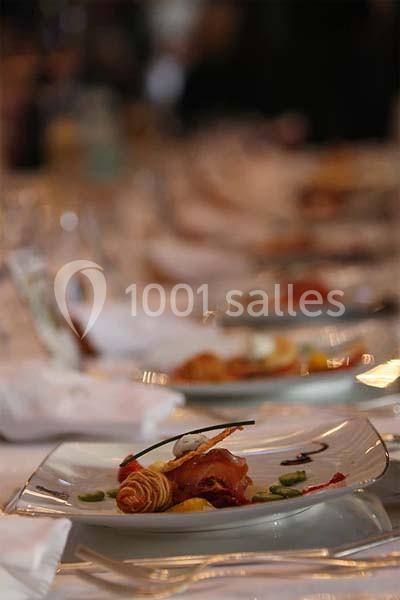 Plat gastronomique dressé avec soin sur une assiette, entouré d'autres plats sur une table élégamment dressée.