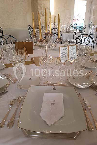 Table élégamment dressée avec vaisselle blanche, couverts dorés, serviettes pliées et chandeliers dorés.