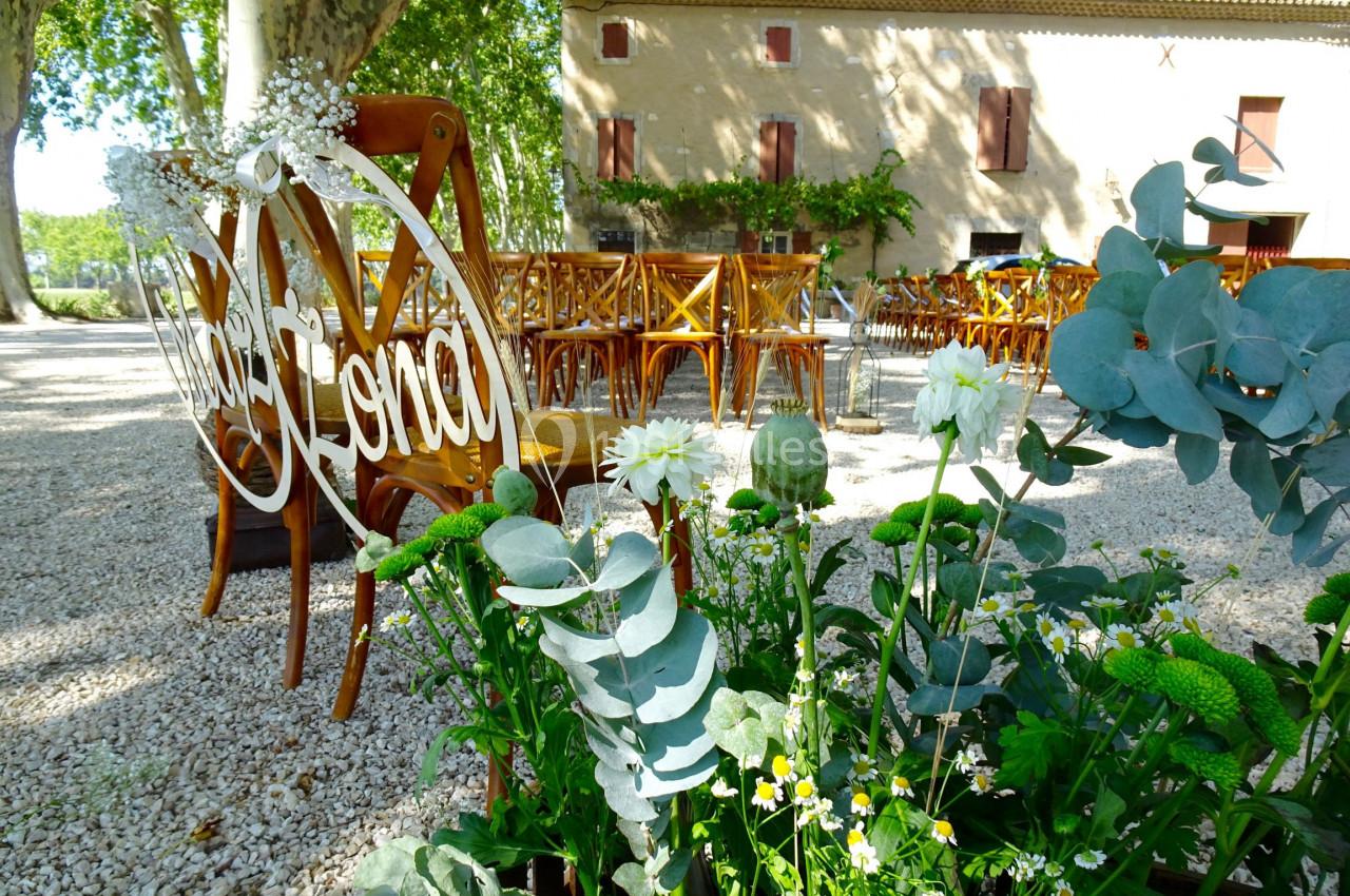 Chaises en bois disposées en extérieur pour un événement, avec des fleurs et une décoration en avant-plan.
