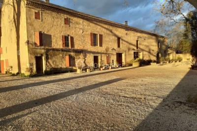 Colonne en pierre sur un socle dans un parc arboré, entourée de pelouse et d'arbres feuillus.
