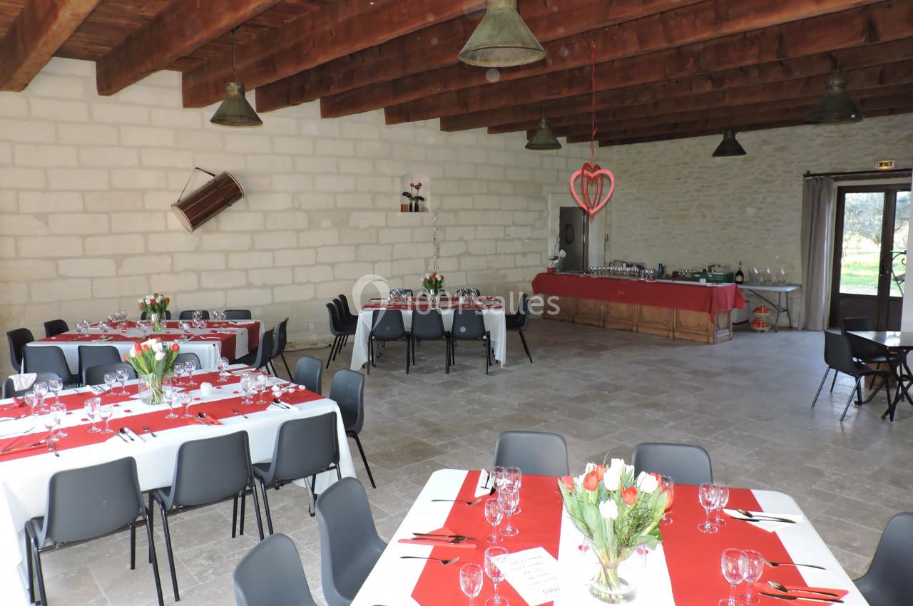 Salle de réception décorée avec des tables dressées, nappes rouges et blanches, et un buffet en arrière-plan.
