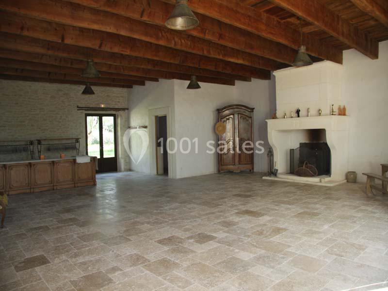 Grande pièce avec sol en pierre, plafond en bois, cheminée, armoire en bois et comptoir près d'une porte vitrée.