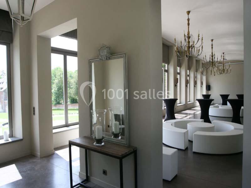 Intérieur lumineux avec un miroir, une console décorée de bougies et un espace aménagé avec des sièges blancs et des lustres.