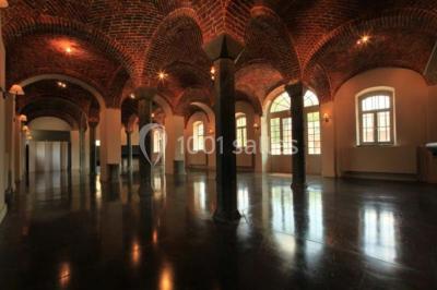 Cour pavée éclairée par des bougies et lumières chaudes, avec un bâtiment historique en arrière-plan, de nuit.