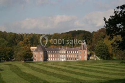 Cour pavée éclairée par des bougies et lumières chaudes, avec un bâtiment historique en arrière-plan, de nuit.