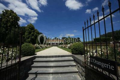Cour pavée éclairée par des bougies et lumières chaudes, avec un bâtiment historique en arrière-plan, de nuit.