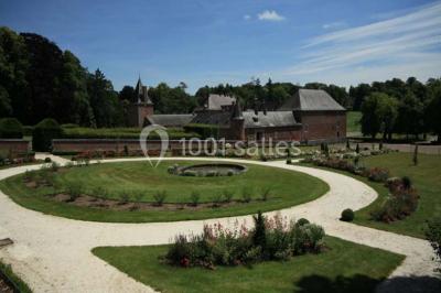 Cour pavée éclairée par des bougies et lumières chaudes, avec un bâtiment historique en arrière-plan, de nuit.