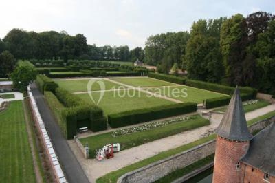 Cour pavée éclairée par des bougies et lumières chaudes, avec un bâtiment historique en arrière-plan, de nuit.