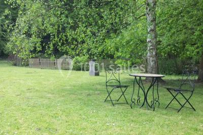 Roses roses et blanches en gros plan devant une pelouse et des arbres verdoyants sous un ciel clair.