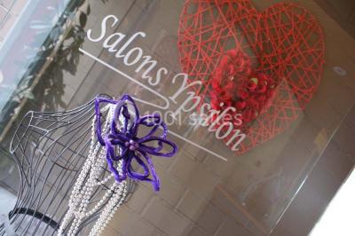 Roses roses et blanches en gros plan devant une pelouse et des arbres verdoyants sous un ciel clair.