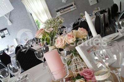 Roses roses et blanches en gros plan devant une pelouse et des arbres verdoyants sous un ciel clair.