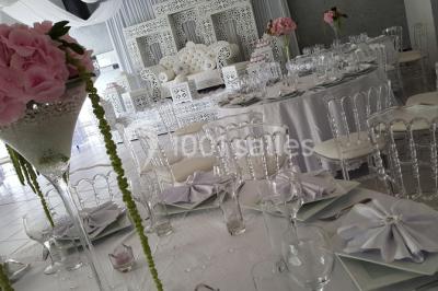 Roses roses et blanches en gros plan devant une pelouse et des arbres verdoyants sous un ciel clair.