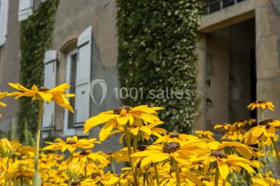 Salon rustique avec poutres apparentes, cheminée, mobilier en cuir et table basse en bois rouge dans un cadre chaleureux.