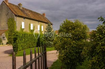 Salon rustique avec poutres apparentes, cheminée, mobilier en cuir et table basse en bois rouge dans un cadre chaleureux.