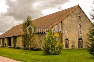 Salon rustique avec poutres apparentes, cheminée, mobilier en cuir et table basse en bois rouge dans un cadre chaleureux.