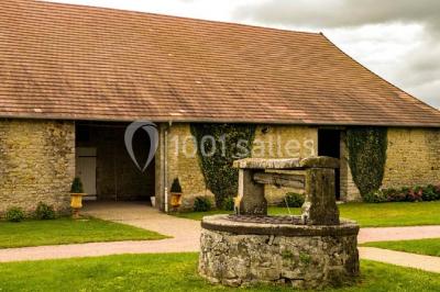 Salon rustique avec poutres apparentes, cheminée, mobilier en cuir et table basse en bois rouge dans un cadre chaleureux.