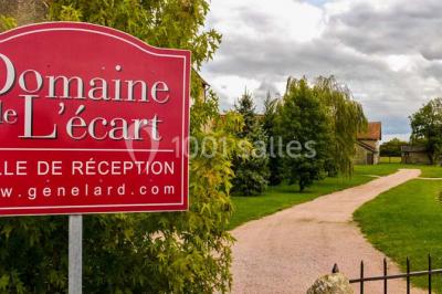Salon rustique avec poutres apparentes, cheminée, mobilier en cuir et table basse en bois rouge dans un cadre chaleureux.