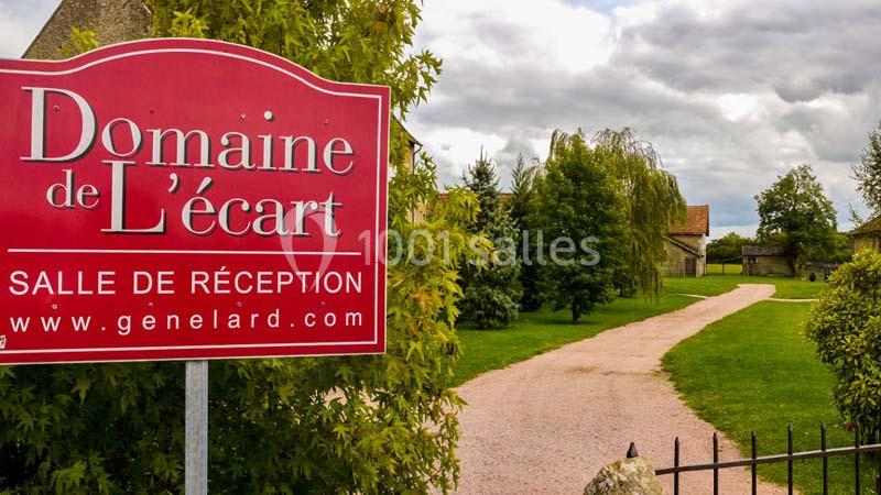 Panneau rouge indiquant ’Domaine de l'écart, salle de réception’ devant une allée bordée de verdure et bâtiments.