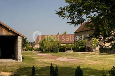Salon rustique avec poutres apparentes, cheminée, mobilier en cuir et table basse en bois rouge dans un cadre chaleureux.