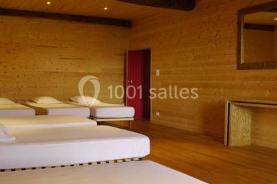 Salon rustique avec poutres apparentes, cheminée, mobilier en cuir et table basse en bois rouge dans un cadre chaleureux.