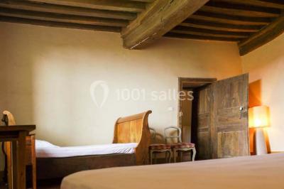 Salon rustique avec poutres apparentes, cheminée, mobilier en cuir et table basse en bois rouge dans un cadre chaleureux.