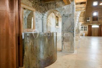 Salon rustique avec poutres apparentes, cheminée, mobilier en cuir et table basse en bois rouge dans un cadre chaleureux.