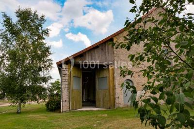 Salon rustique avec poutres apparentes, cheminée, mobilier en cuir et table basse en bois rouge dans un cadre chaleureux.