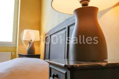 Salon rustique avec poutres apparentes, cheminée, mobilier en cuir et table basse en bois rouge dans un cadre chaleureux.