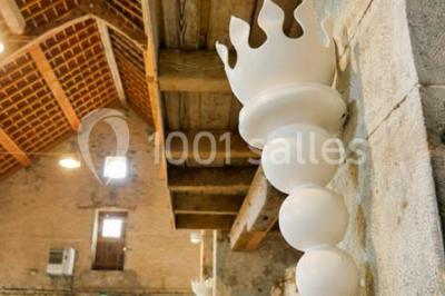 Salon rustique avec poutres apparentes, cheminée, mobilier en cuir et table basse en bois rouge dans un cadre chaleureux.