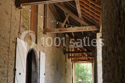 Salon rustique avec poutres apparentes, cheminée, mobilier en cuir et table basse en bois rouge dans un cadre chaleureux.