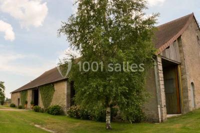 Salon rustique avec poutres apparentes, cheminée, mobilier en cuir et table basse en bois rouge dans un cadre chaleureux.