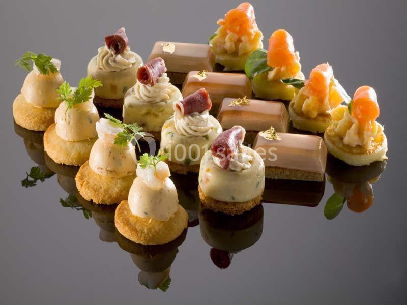 Assortiment de bouchées salées élégamment présentées sur une surface réfléchissante.