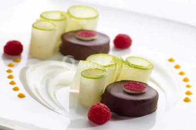 Dessert composé d'un gâteau aux fruits, d'une glace, d'une tuile décorative et d'une sauce artistique au chocolat et caramel.