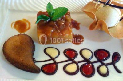 Dessert composé d'un gâteau aux fruits, d'une glace, d'une tuile décorative et d'une sauce artistique au chocolat et caramel.