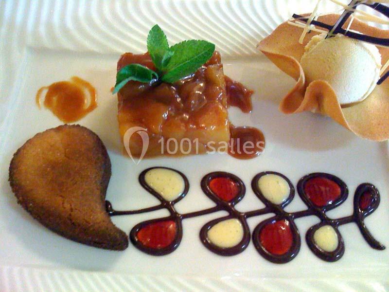 Dessert composé d'un gâteau aux fruits, d'une glace, d'une tuile décorative et d'une sauce artistique au chocolat et caramel.