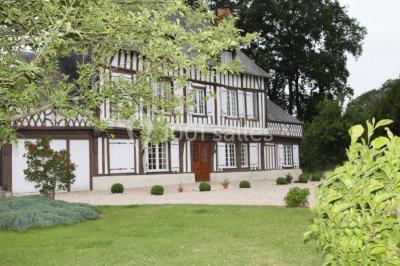 Bâtiment illuminé de nuit avec des façades vitrées et un toit en pente, entouré d'obscurité.