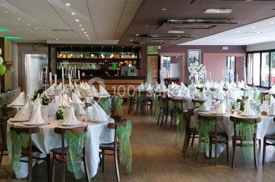 Bâtiment illuminé de nuit avec des façades vitrées et un toit en pente, entouré d'obscurité.