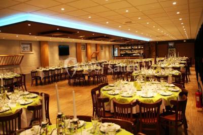 Bâtiment illuminé de nuit avec des façades vitrées et un toit en pente, entouré d'obscurité.