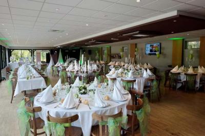 Bâtiment illuminé de nuit avec des façades vitrées et un toit en pente, entouré d'obscurité.