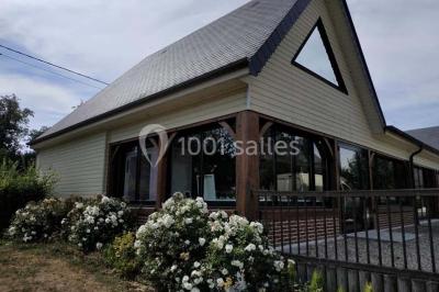 Bâtiment illuminé de nuit avec des façades vitrées et un toit en pente, entouré d'obscurité.