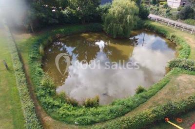 Bâtiment illuminé de nuit avec des façades vitrées et un toit en pente, entouré d'obscurité.