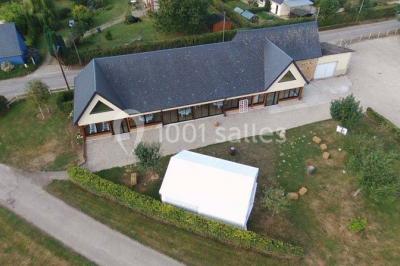 Bâtiment illuminé de nuit avec des façades vitrées et un toit en pente, entouré d'obscurité.