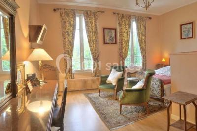 Canal bordé d'arbres avec une écluse centrale et un paysage verdoyant sous un ciel partiellement nuageux.