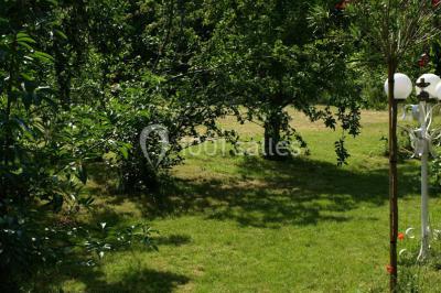 Canal bordé d'arbres avec une écluse centrale et un paysage verdoyant sous un ciel partiellement nuageux.