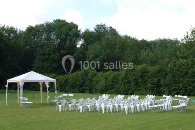 Arche de cérémonie décorée de fleurs blanches et de voilages verts, installée dans un jardin ombragé.