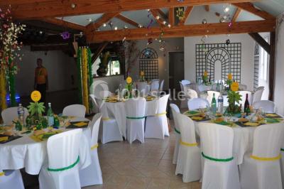 Arche de cérémonie décorée de fleurs blanches et de voilages verts, installée dans un jardin ombragé.