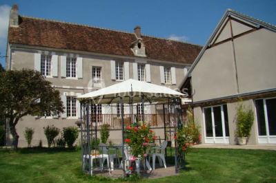 Arche de cérémonie décorée de fleurs blanches et de voilages verts, installée dans un jardin ombragé.