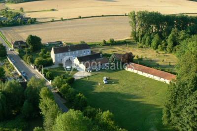 Arche de cérémonie décorée de fleurs blanches et de voilages verts, installée dans un jardin ombragé.